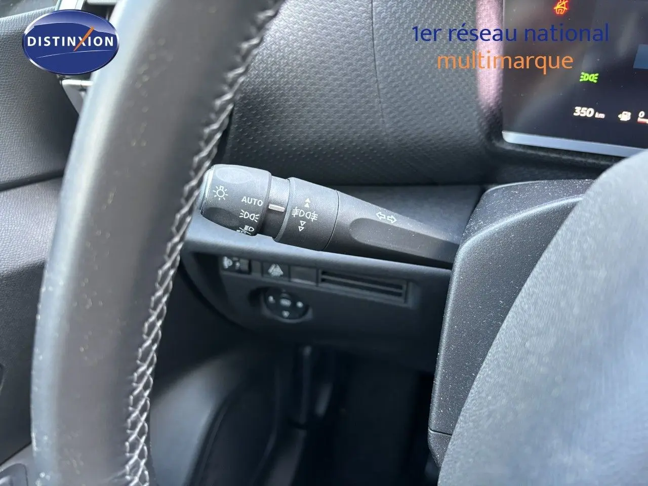 Gros plan sur la commande des feux et clignotants côté gauche du volant dans l'habitacle d'une Citroën C4 gris Artense 2022.