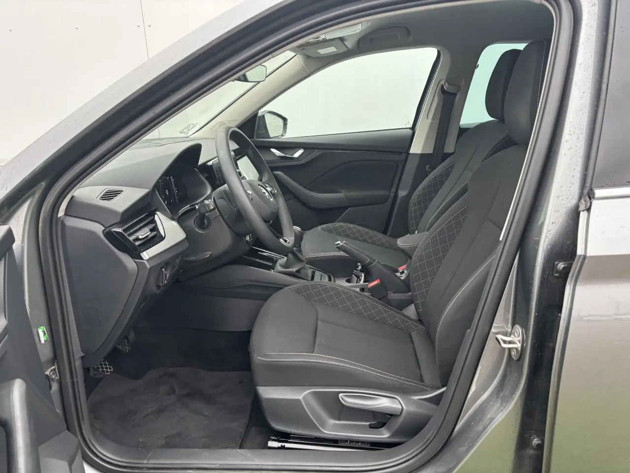 Intérieur côté conducteur du Skoda Kamiq gris graphite, sièges tissu Ambition noirs avec surpiqûres et volant cuir multifonctions.