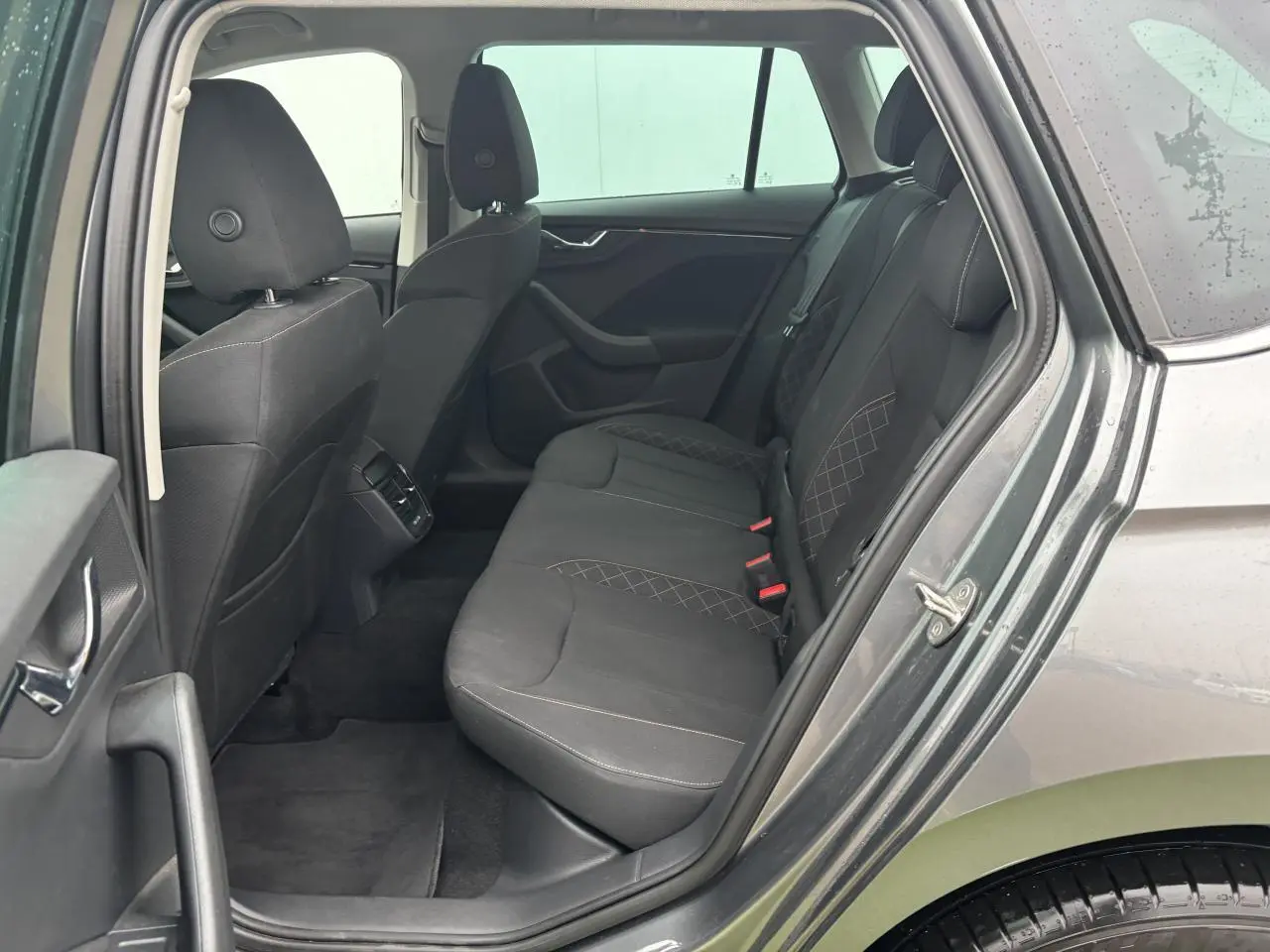 Vue côté gauche arrière du Skoda Kamiq gris graphite métal, montrant les sièges arrière en tissu avec surpiqûres croisées.