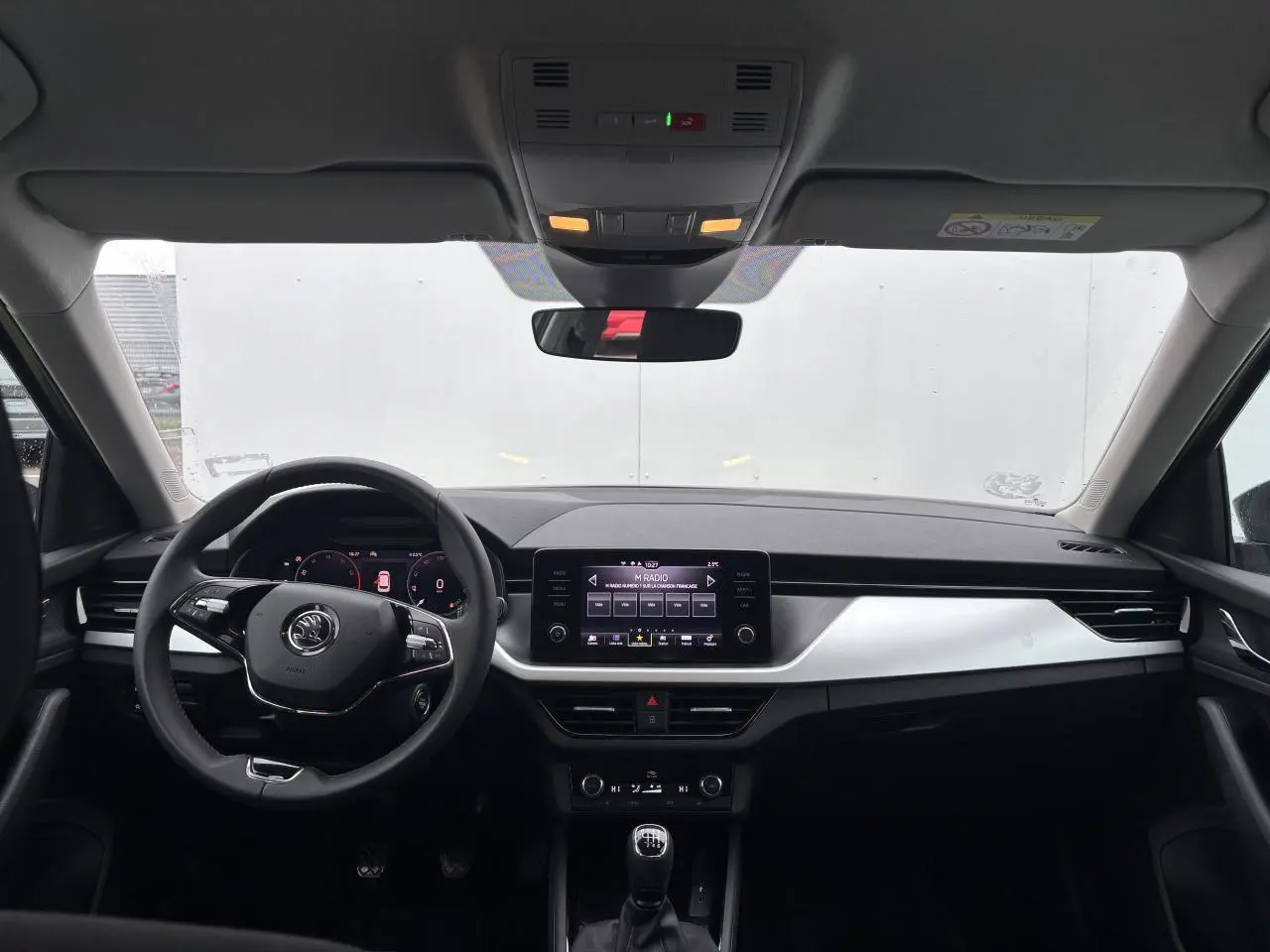 Intérieur avant du Skoda Kamiq 2024 avec tableau de bord noir, écran tactile central et volant cuir multifonctions.