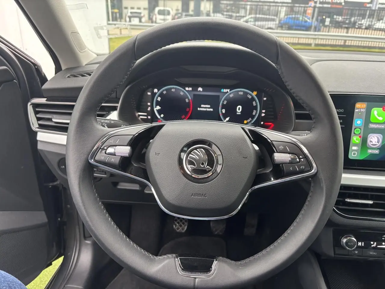 Vue centrée sur le volant cuir noir du Skoda Kamiq 2024 avec tableau de bord numérique et écran tactile latéral.