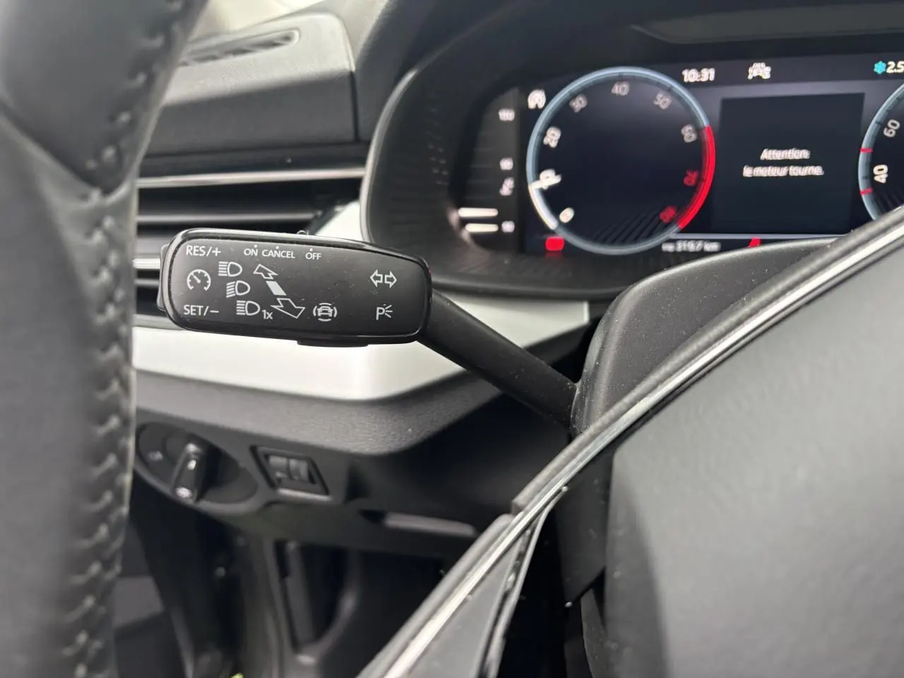 Gros plan sur la commande de régulateur de vitesse à gauche du volant cuir dans l'habitacle du Skoda Kamiq 2024.