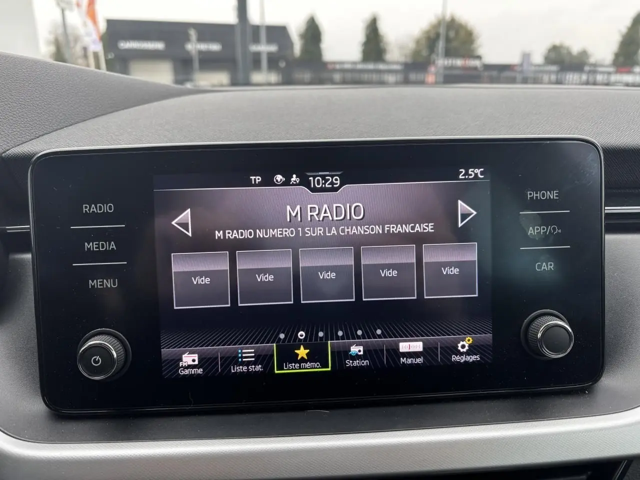 Écran tactile central du Skoda Kamiq 2024 affichant la radio M Radio avec commandes autour et finition gris graphite.