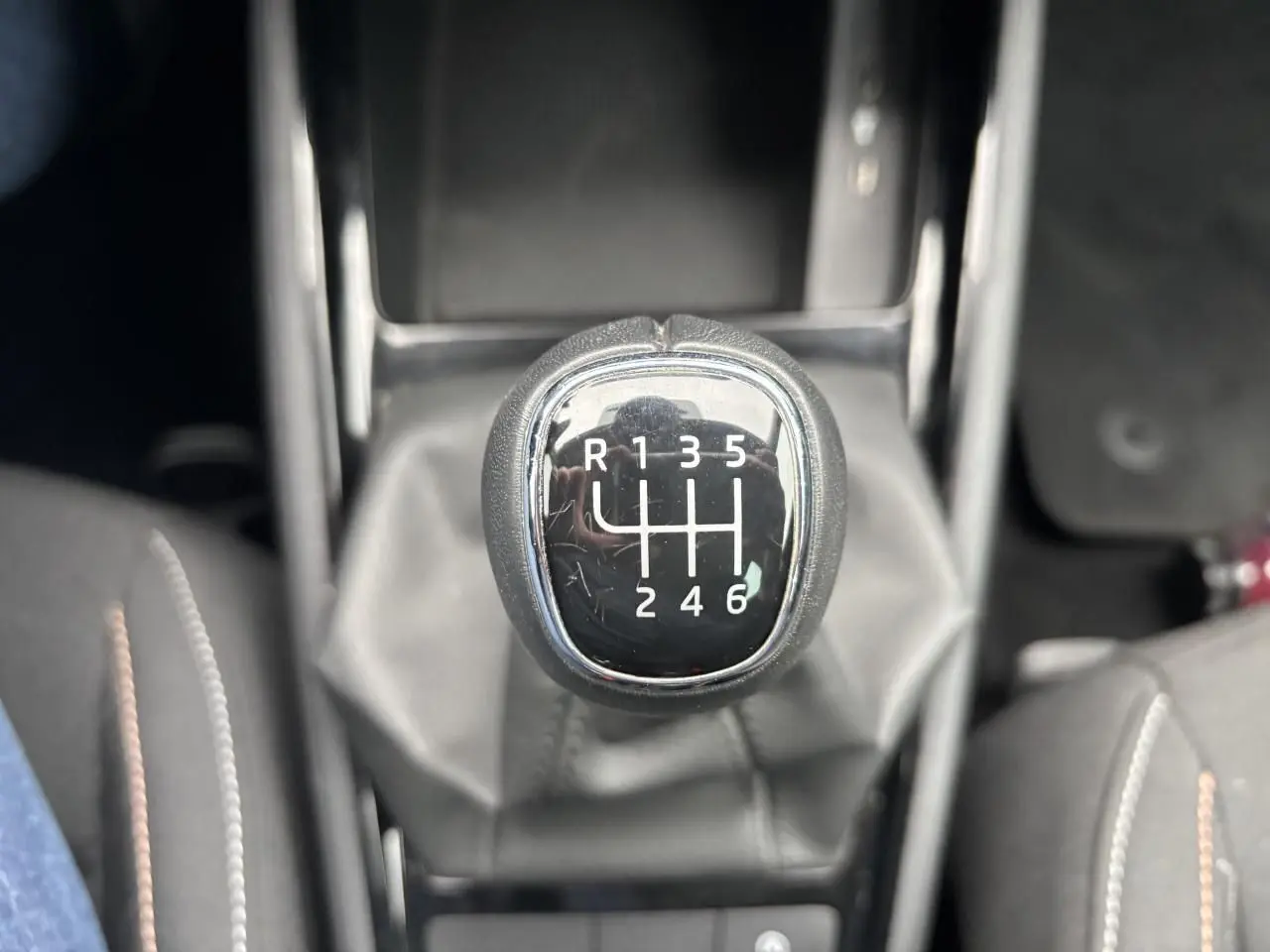 Le levier de vitesses manuel noir de la Skoda Kamiq 2024 avec marquages blancs, entouré de sellerie tissu grise.