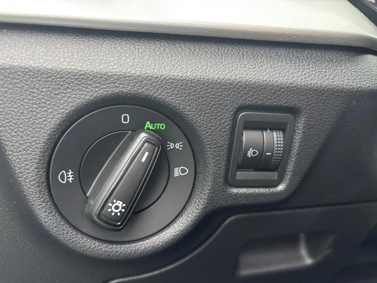 Gros plan sur la commande d’éclairage avec réglage automatique dans l’habitacle gris foncé du Skoda Kamiq 2024.