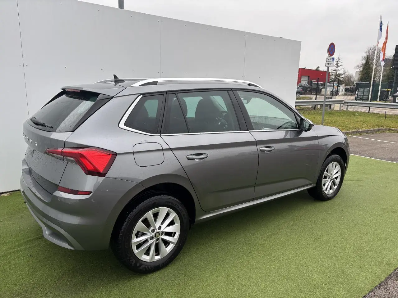 Vue 3/4 arrière droite d'un Skoda Kamiq gris graphite métallisé avec jantes alliage 17 pouces sur parking.