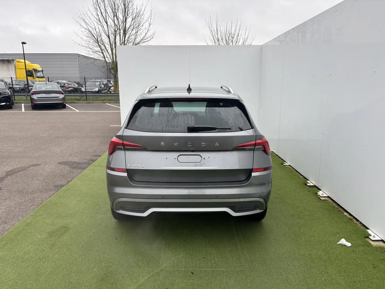 Vue arrière d'un Skoda Kamiq gris graphite métallisé avec feux LED et antenne aileron de requin sur parking.