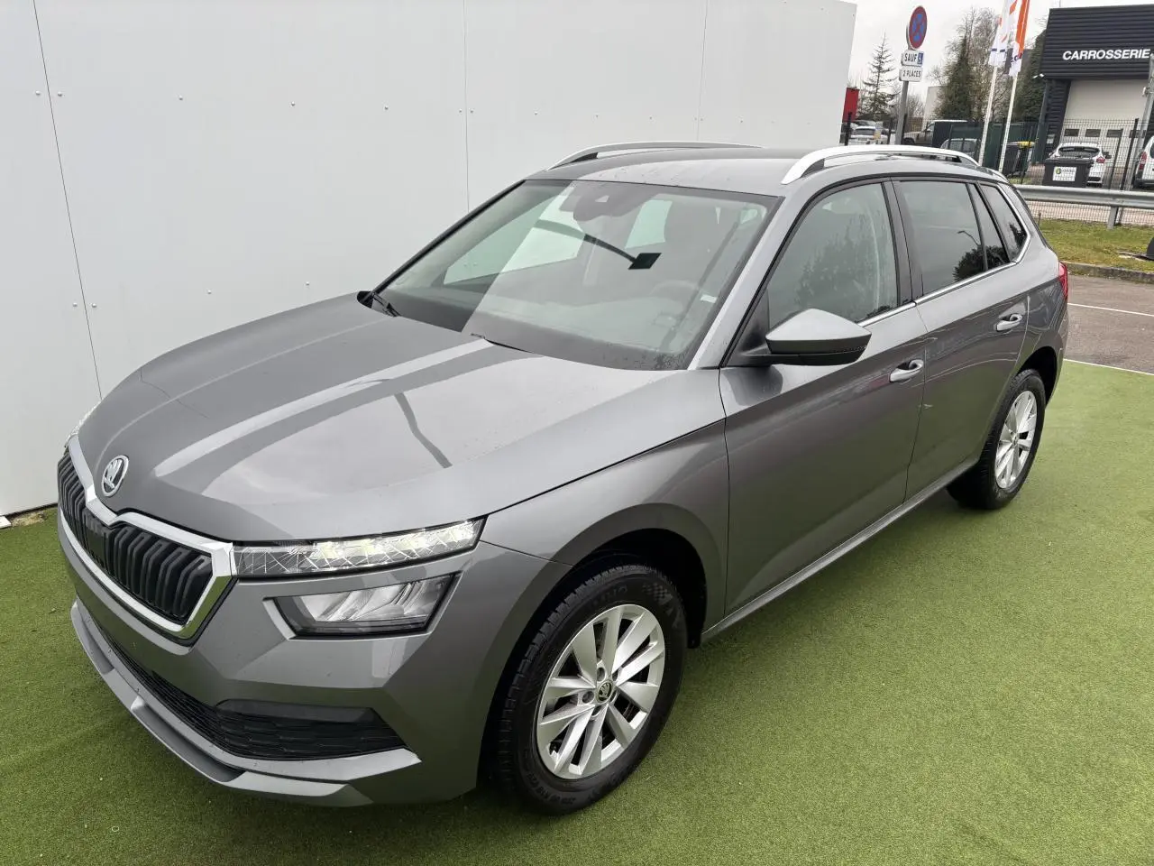 Vue 3/4 avant droite d'un Skoda Kamiq gris graphite métallisé avec jantes alliage 17 pouces et toit panoramique.
