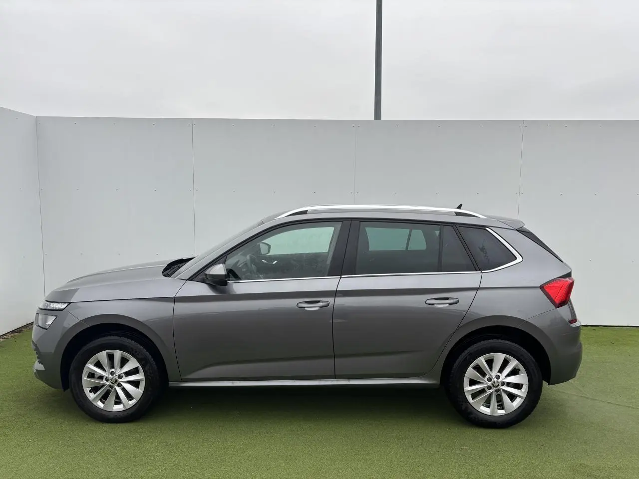 Vue latérale gauche d'un Skoda Kamiq gris graphite métallisé avec jantes alliage 17 pouces sur fond neutre.