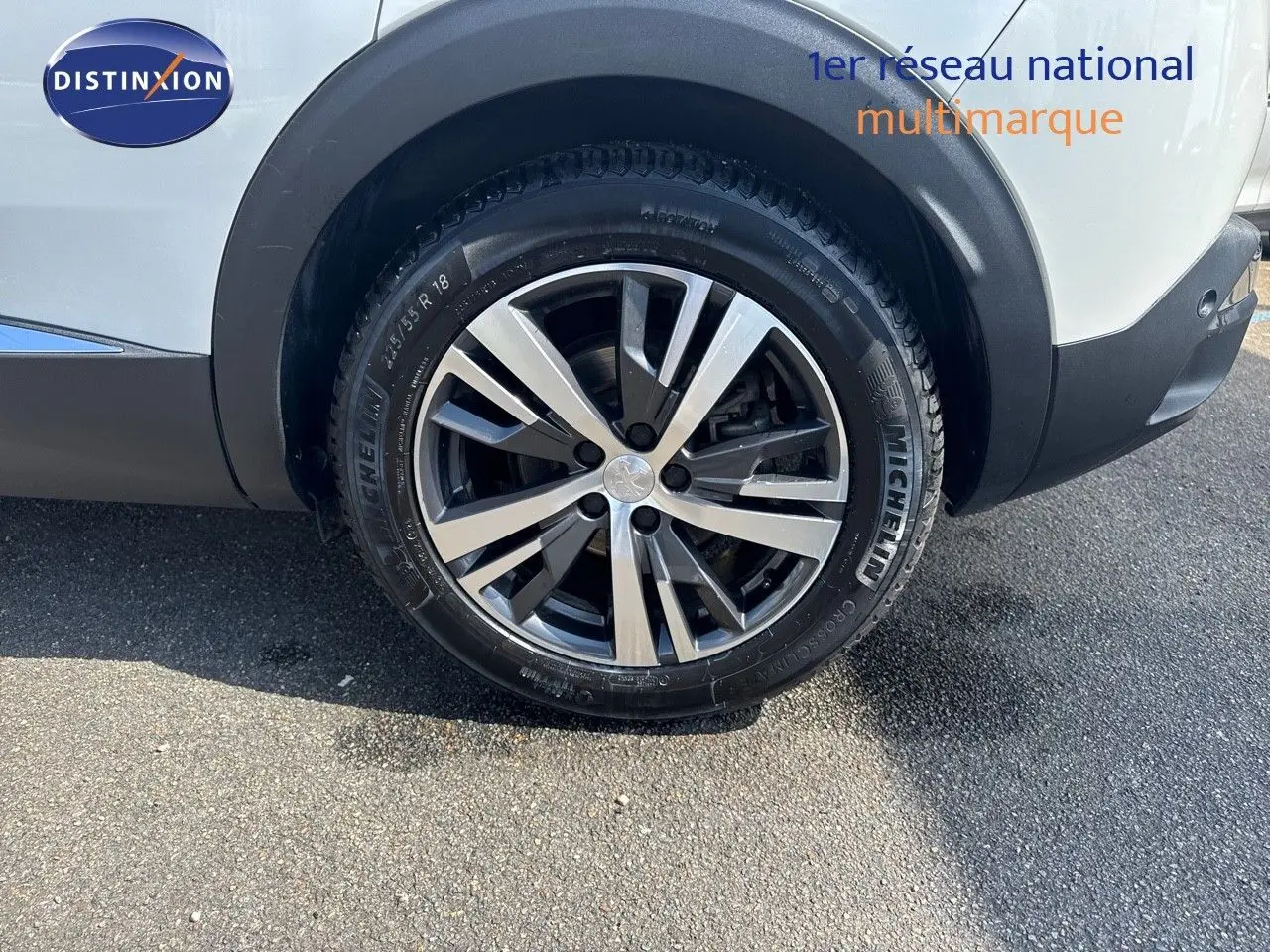 Gros plan sur la roue arrière droite du Peugeot 3008 blanc nacré, mettant en valeur la jante alliage 18 pouces et le pneu Michelin.