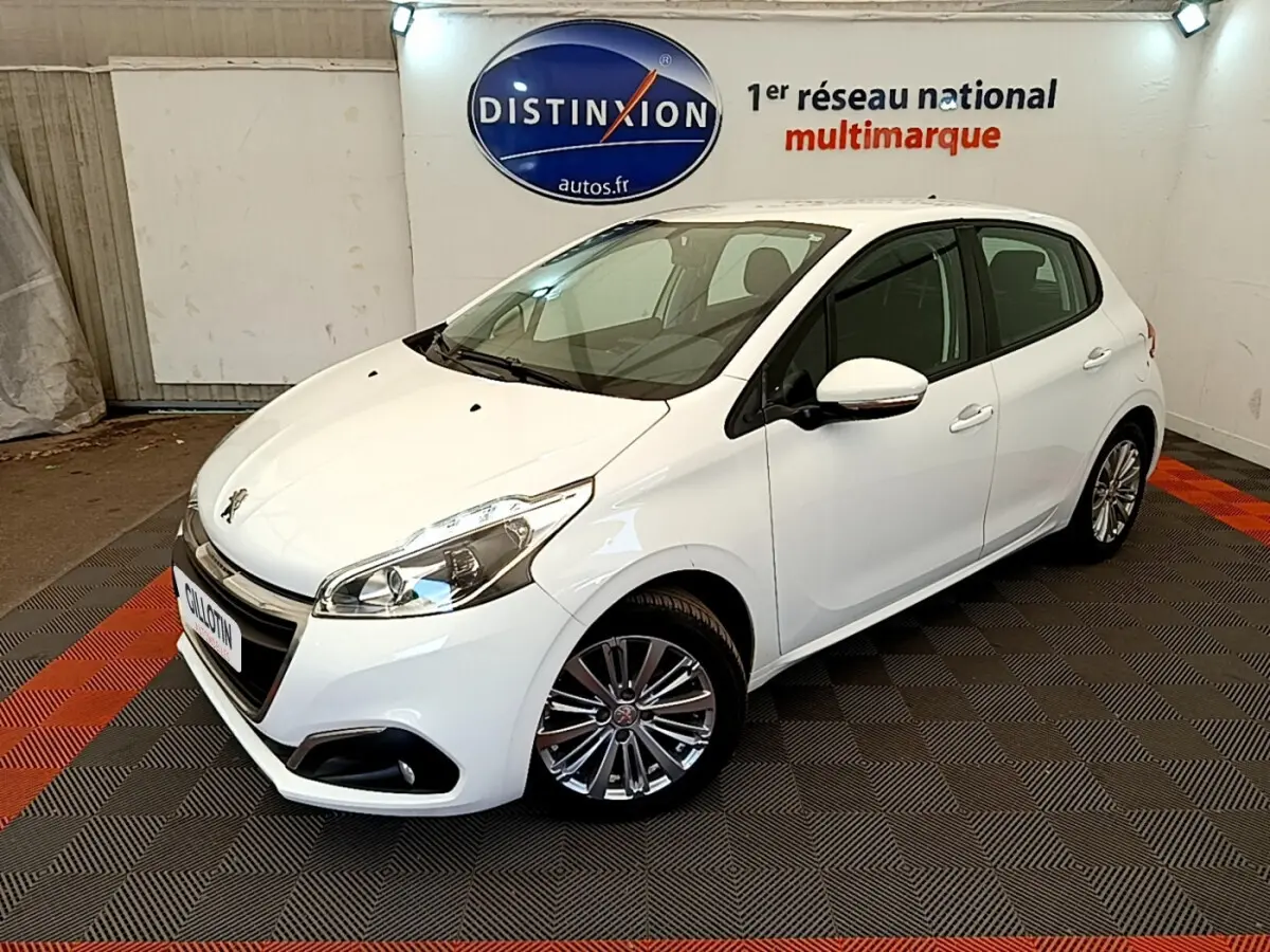 Peugeot 208 Puretech 82 Signature blanc vue 3/4 avant droit dans un showroom avec sol à damier noir et rouge.