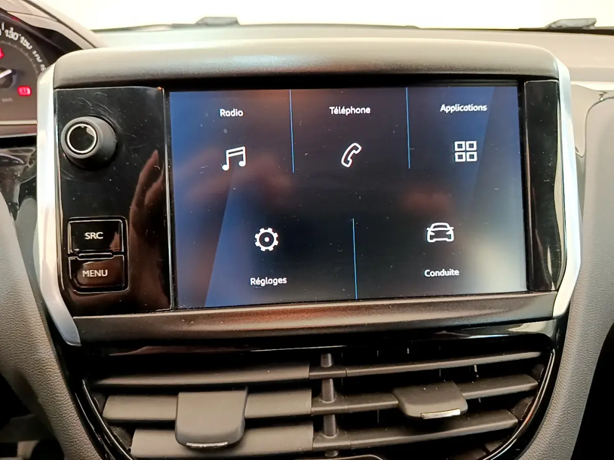 Écran tactile central affichant les options radio, téléphone et applications dans l'habitacle d'une Peugeot 208 blanche.