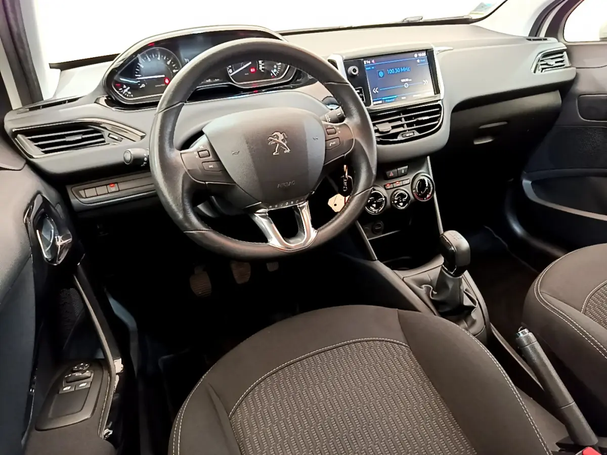 Intérieur de la Peugeot 208 Puretech 82 Signature 2019, vue côté conducteur sur le tableau de bord et volant cuir noir.