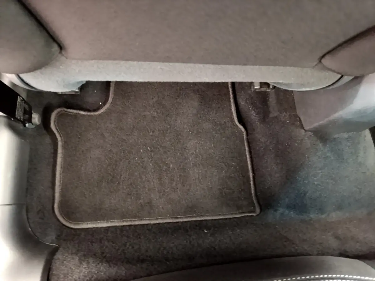 Plancher arrière avec tapis de sol noir sous la banquette d'une Peugeot 208 Puretech 82 Signature blanche de 2019.