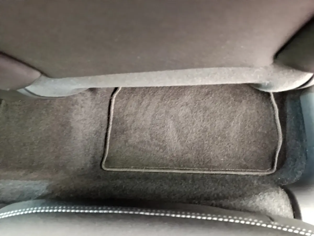 Vue rapprochée du tapis de sol gris foncé et de la base d'un siège avant sur Peugeot 208 Puretech 82 Signature blanc.