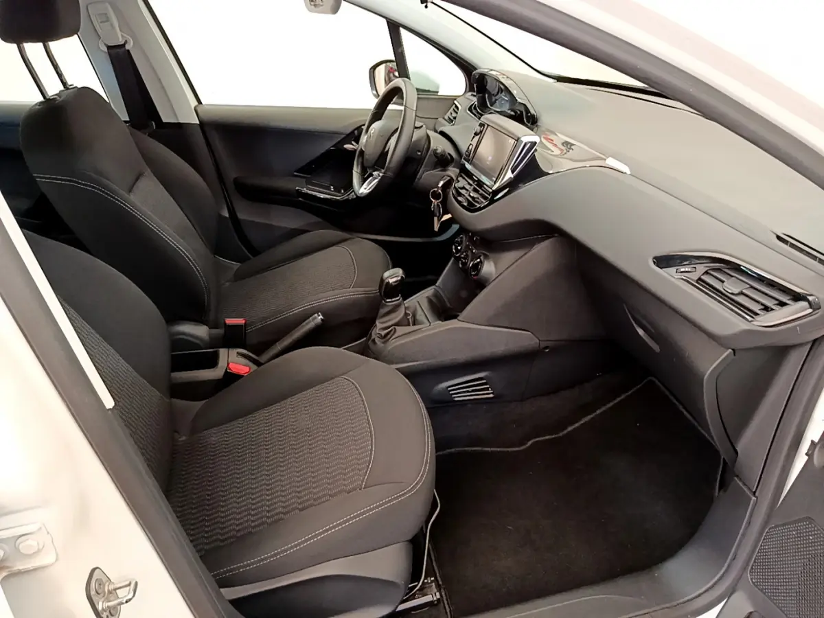 Intérieur noir de la Peugeot 208 Puretech 82 Signature 2019 vu côté passager, avec tableau de bord moderne et écran tactile.