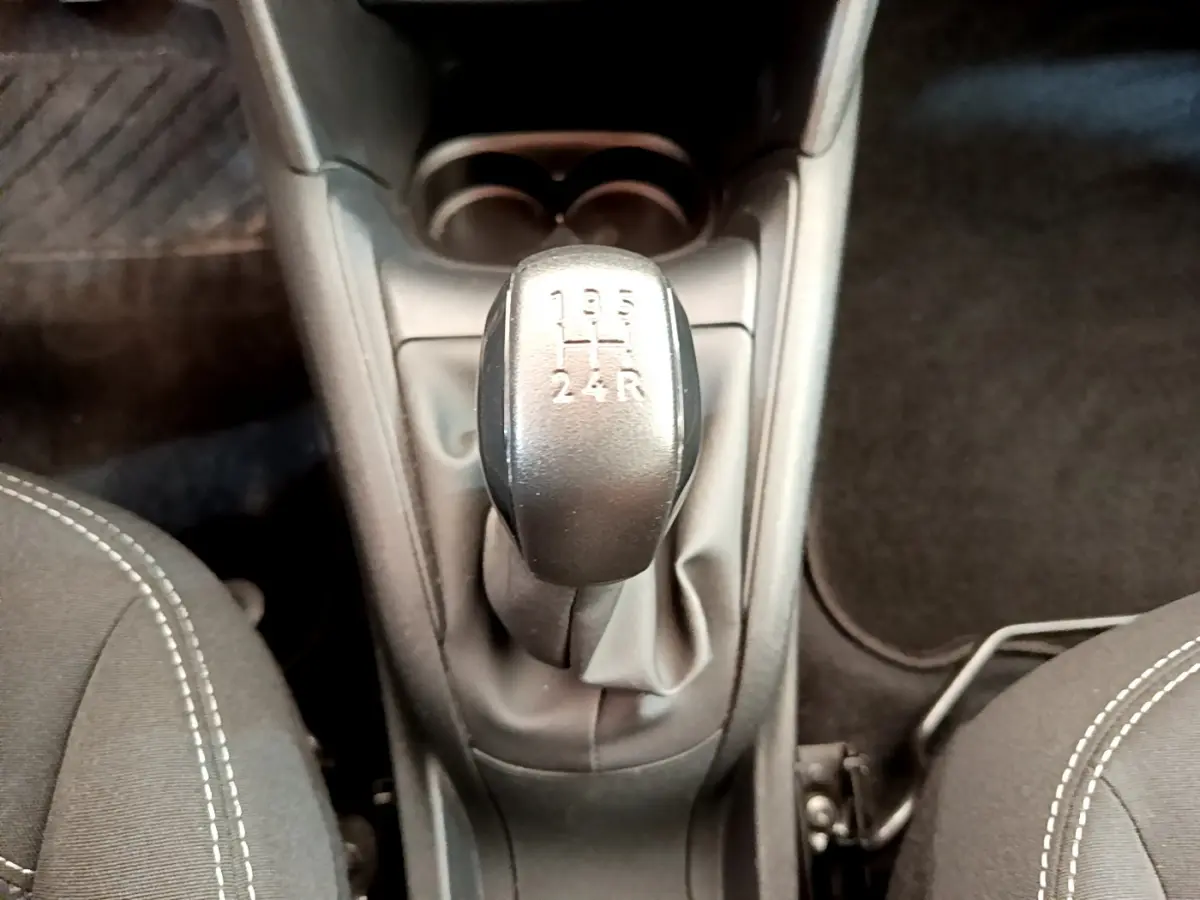 Le levier de vitesses manuel noir de la Peugeot 208 Puretech 82 Signature vu de dessus entre les sièges avant gris.