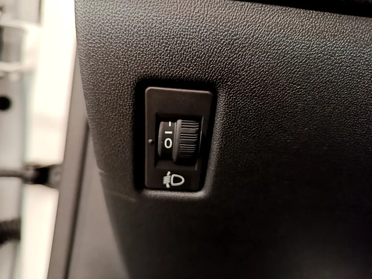 Molette de réglage des phares sur tableau de bord noir d'une Peugeot 208 Puretech 82 Signature blanche de 2019.