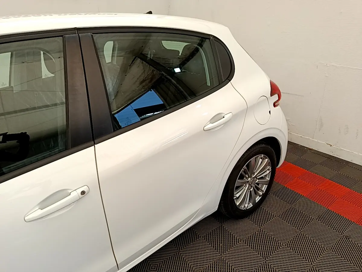 Vue latérale arrière droite d'une Peugeot 208 Puretech 82 Signature blanche avec jante alliage et poignée de porte blanche.