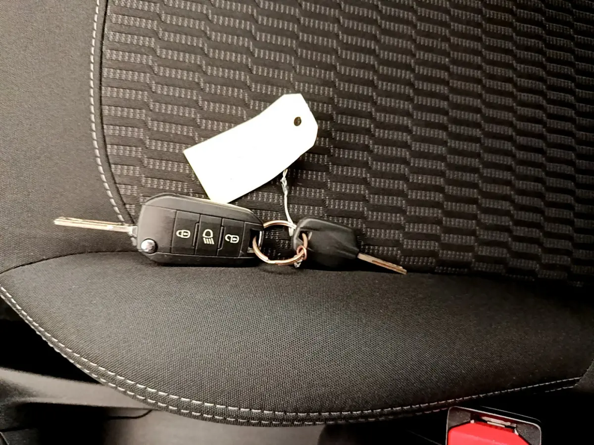Clé de contact posée sur un siège tissu noir à motifs de la Peugeot 208 Puretech 82 Signature 2019.
