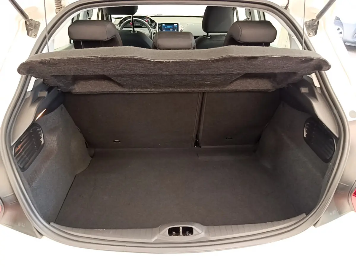 Coffre ouvert d'une Peugeot 208 blanche, vue arrière montrant l'espace de chargement et les sièges arrière.