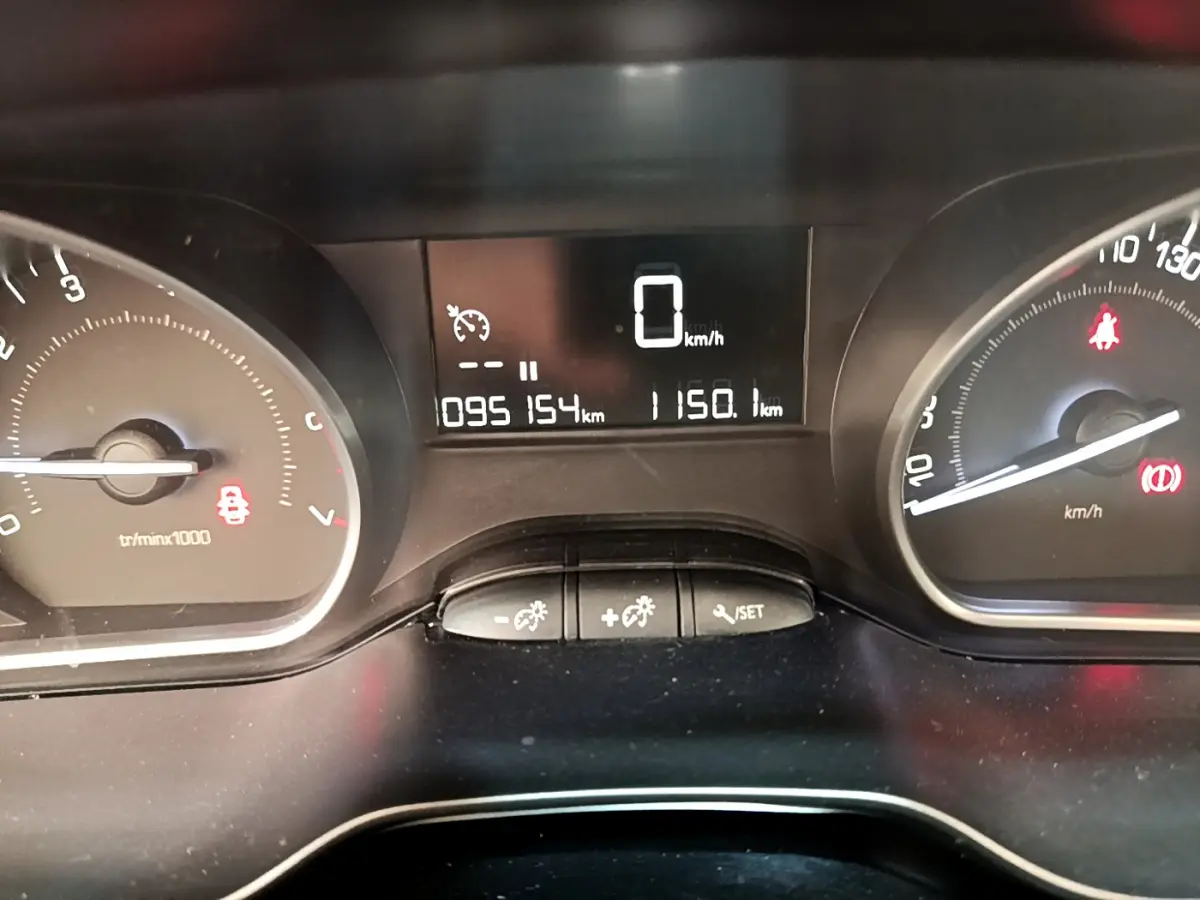 Tableau de bord de Peugeot 208 blanc, affichage numérique au centre avec compteur de vitesse à 0 km/h.