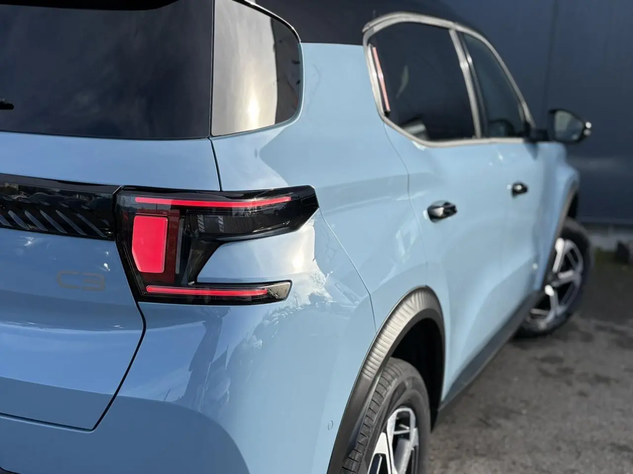 Vue 3/4 arrière droite d'une Citroën C3 Aircross 2025 bleu Monte Carlo avec toit noir et feux arrière LED distinctifs.