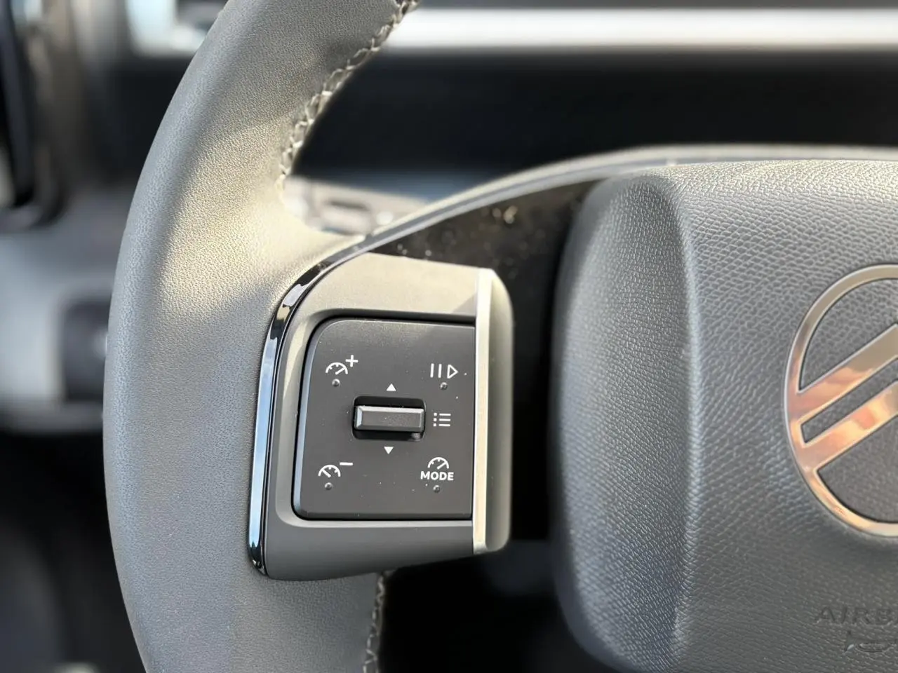Gros plan sur les commandes au volant à gauche du Citroën C3 Aircross Hybrid 2025 avec logo et finition noire.