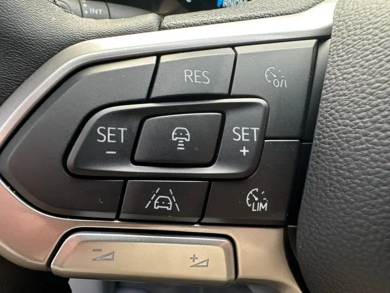Gros plan sur les commandes multifonctions du volant cuir du Volkswagen Transporter FGN gris, boutons de régulateur de vitesse et assistance.