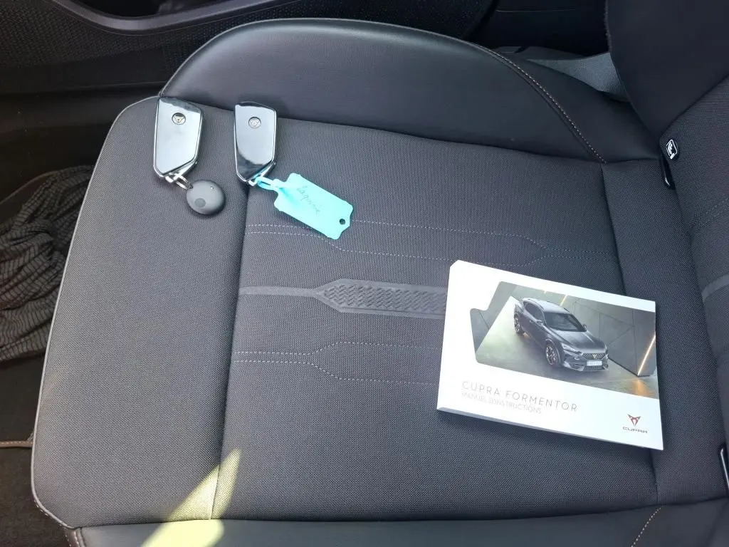 Vue rapprochée du siège avant droit gris foncé avec deux clés et le manuel d'instructions du CUPRA Formentor posé dessus.