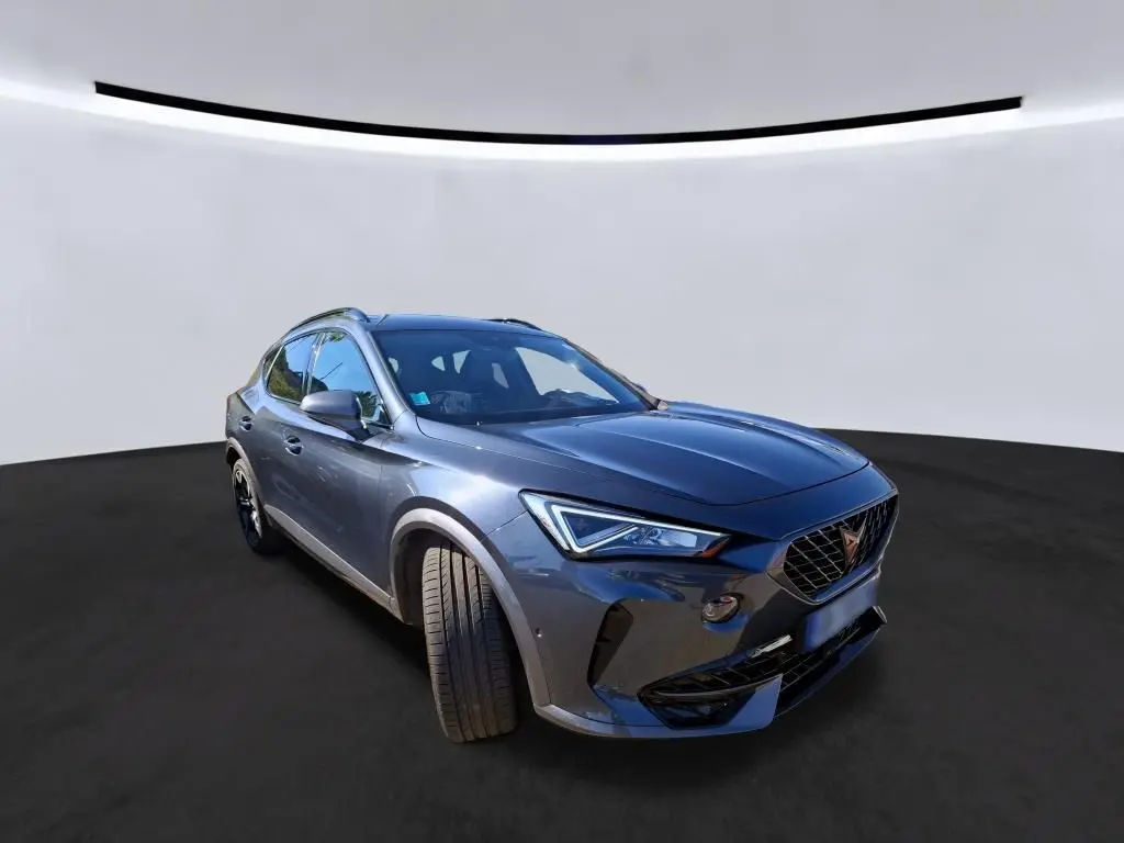 Vue 3/4 avant droit d'une CUPRA Formentor gris métallisé avec phares LED et calandre distinctive en losange.