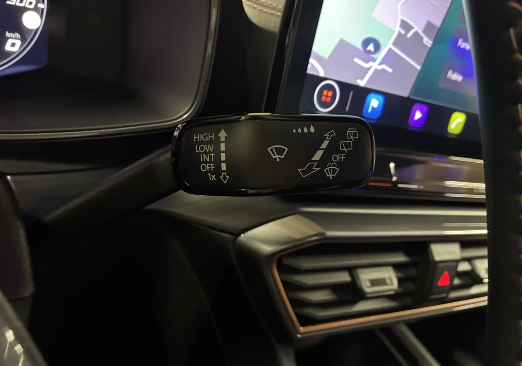 Gros plan sur la commande d’essuie-glace à gauche du volant dans l’habitacle du CUPRA Formentor gris, avec écran tactile en arrière-plan.