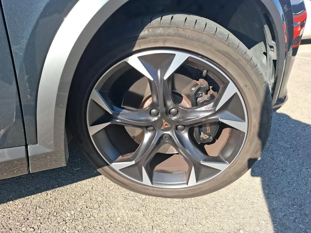 Gros plan sur la roue avant gauche du CUPRA Formentor gris 2023 avec jante alliage noire et logo CUPRA orange.