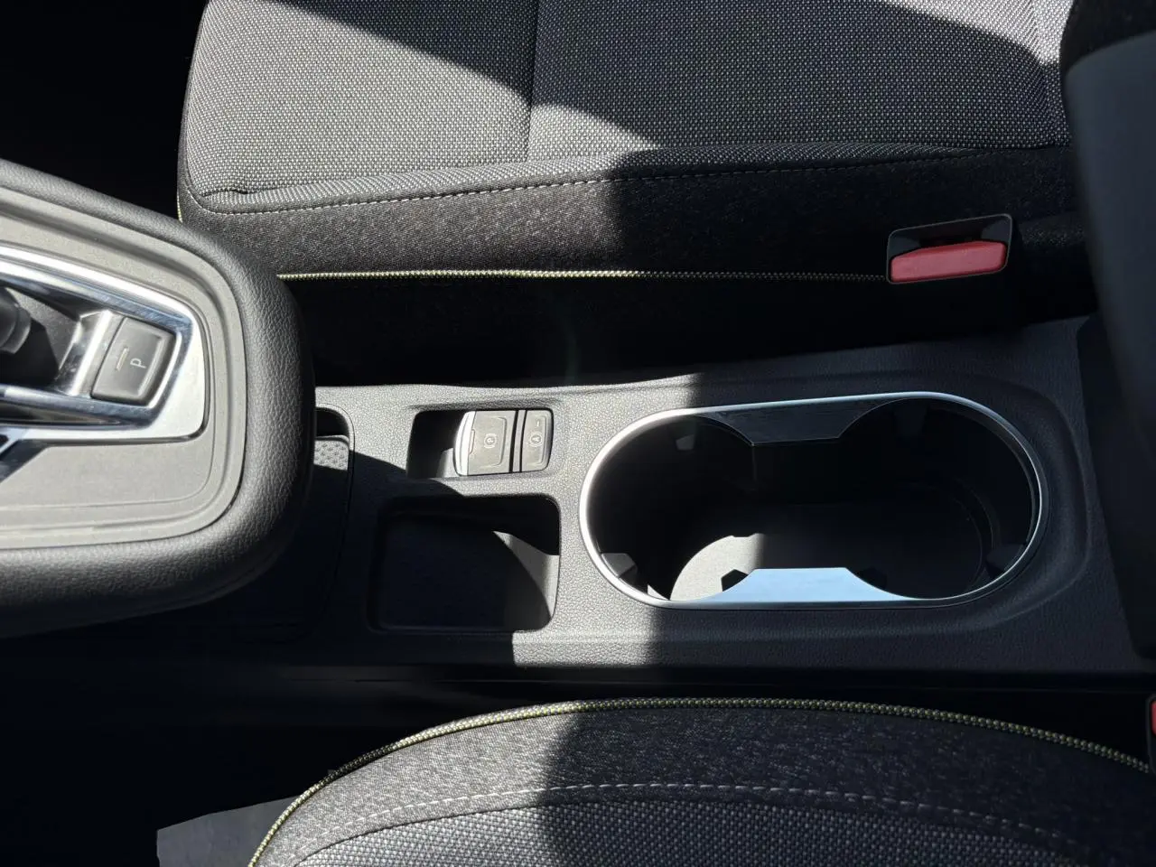 Gros plan sur la console centrale noire du Renault Captur 2025 avec porte-gobelets et bouton frein à main électrique.
