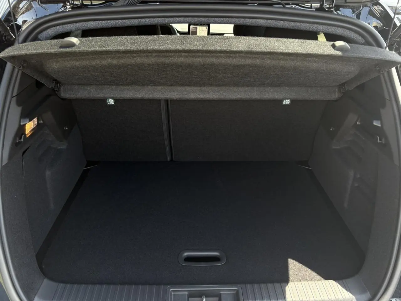 Coffre ouvert vu de l'arrière du Renault Captur noir Étoile, montrant l'espace de chargement vide et la tablette cache-bagages.