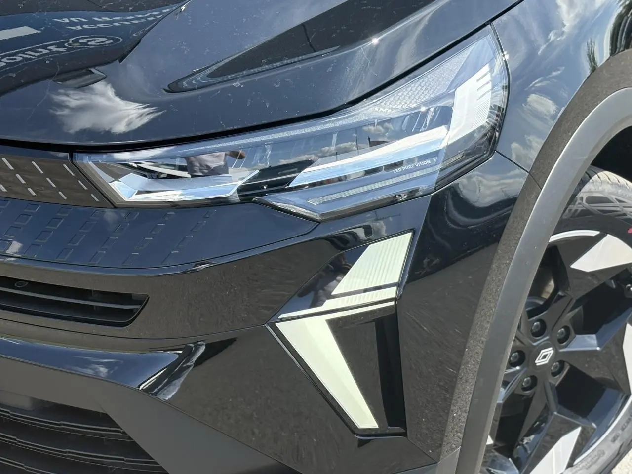 Gros plan sur l'avant droit du Renault Captur noir Étoile, mettant en valeur le phare LED Pure Vision et la jante aluminium 18 pouces.