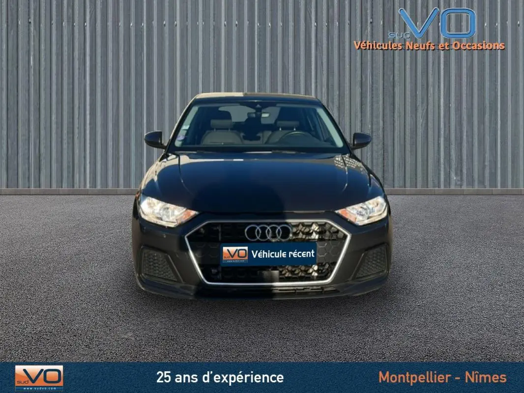 Vue frontale d'une Audi A1 Sportback gris foncé 2019 avec calandre hexagonale et phares halogènes allumés.
