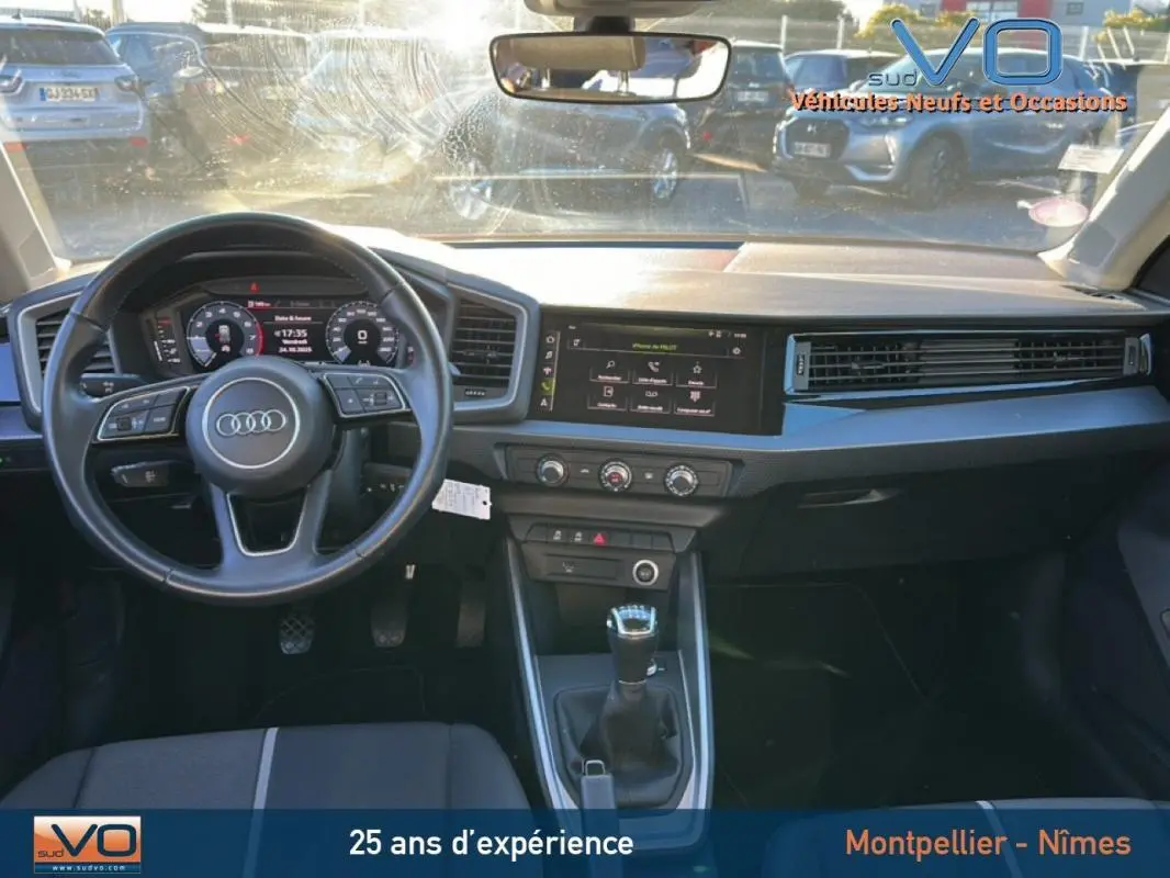 Intérieur de l'Audi A1 Sportback 2019 vu de face, volant cuir, boîte manuelle, écran tactile et cockpit numérique visibles.
