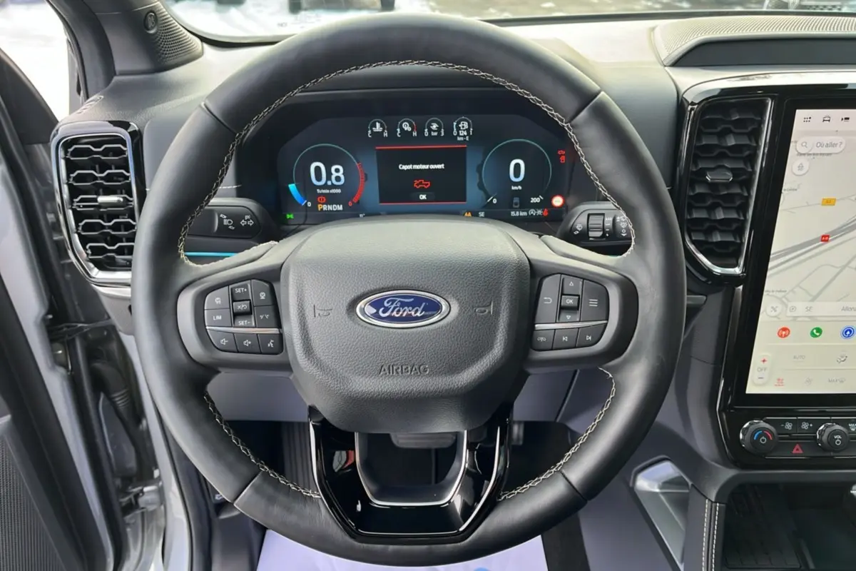 Vue frontale du volant cuir noir du Ford Ranger 2026 avec tableau de bord numérique et écran tactile central.