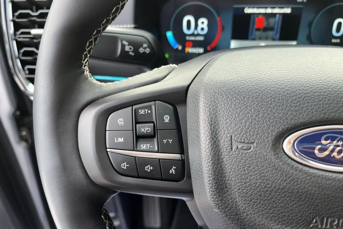 Gros plan sur le volant cuir multifonctions du Ford Ranger 2026, avec commandes de régulateur et tableau de bord numérique visible.