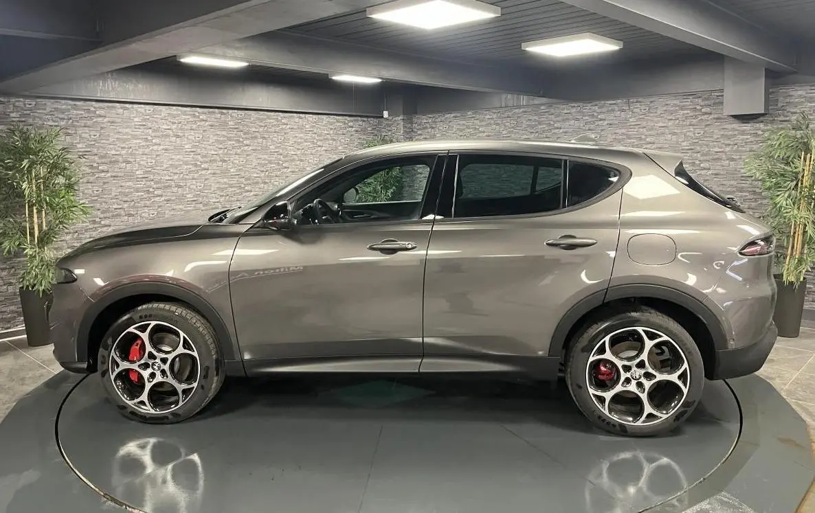 Profil droit d'un Alfa Romeo Tonale gris foncé 2023 avec jantes alliage 19 pouces et étriers rouges visibles.