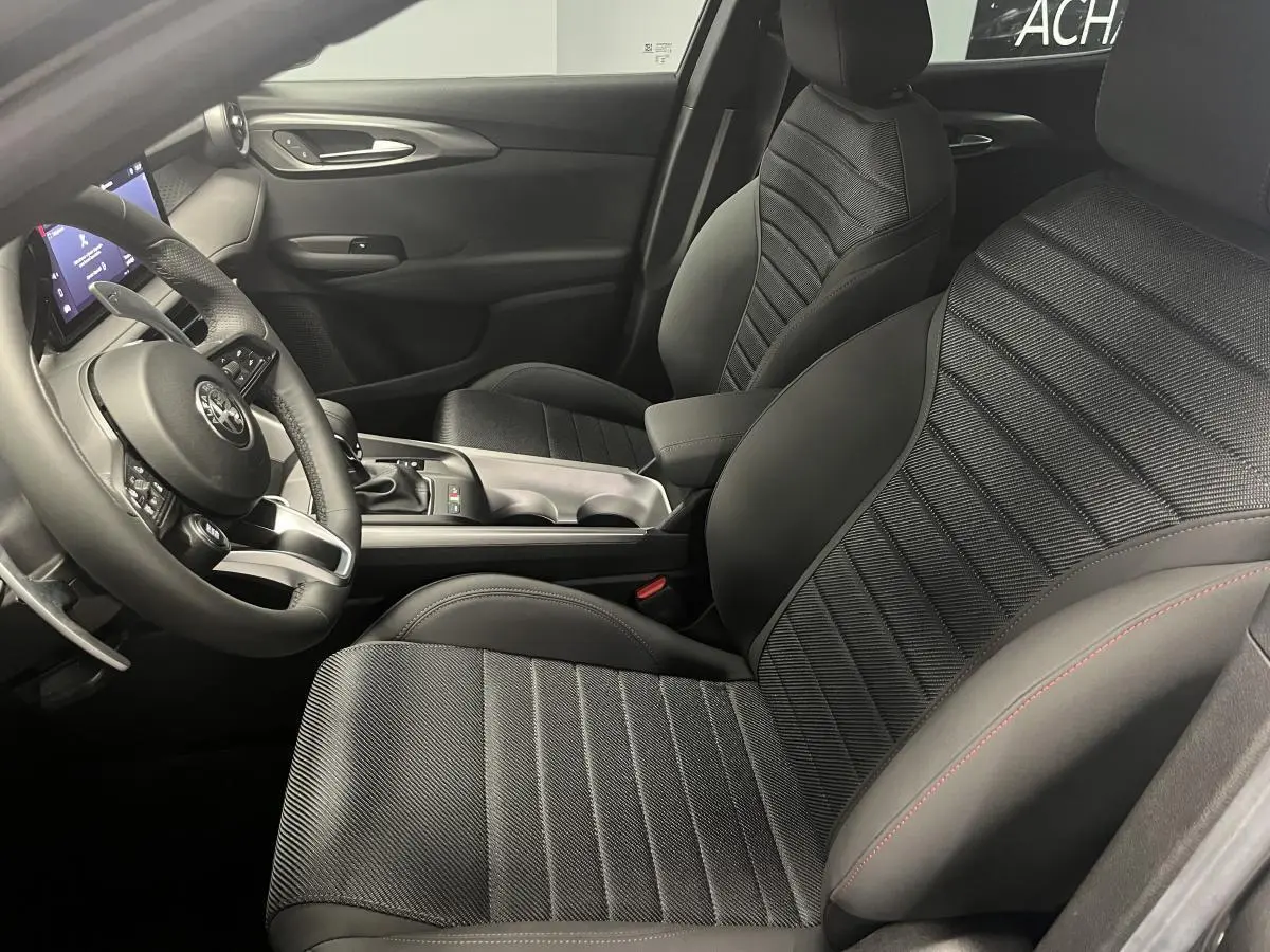 Intérieur de l'Alfa Romeo Tonale 2023, vue côté conducteur, sellerie noire AlfaTec avec surpiqûres rouges et volant sport cuir.