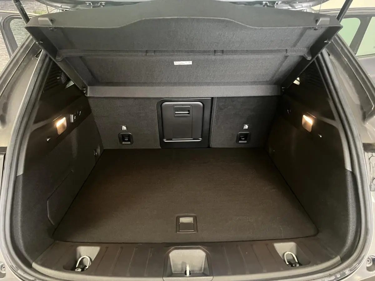 Coffre ouvert d'un Alfa Romeo Tonale gris foncé, vue intérieure montrant un espace de chargement propre et éclairé.