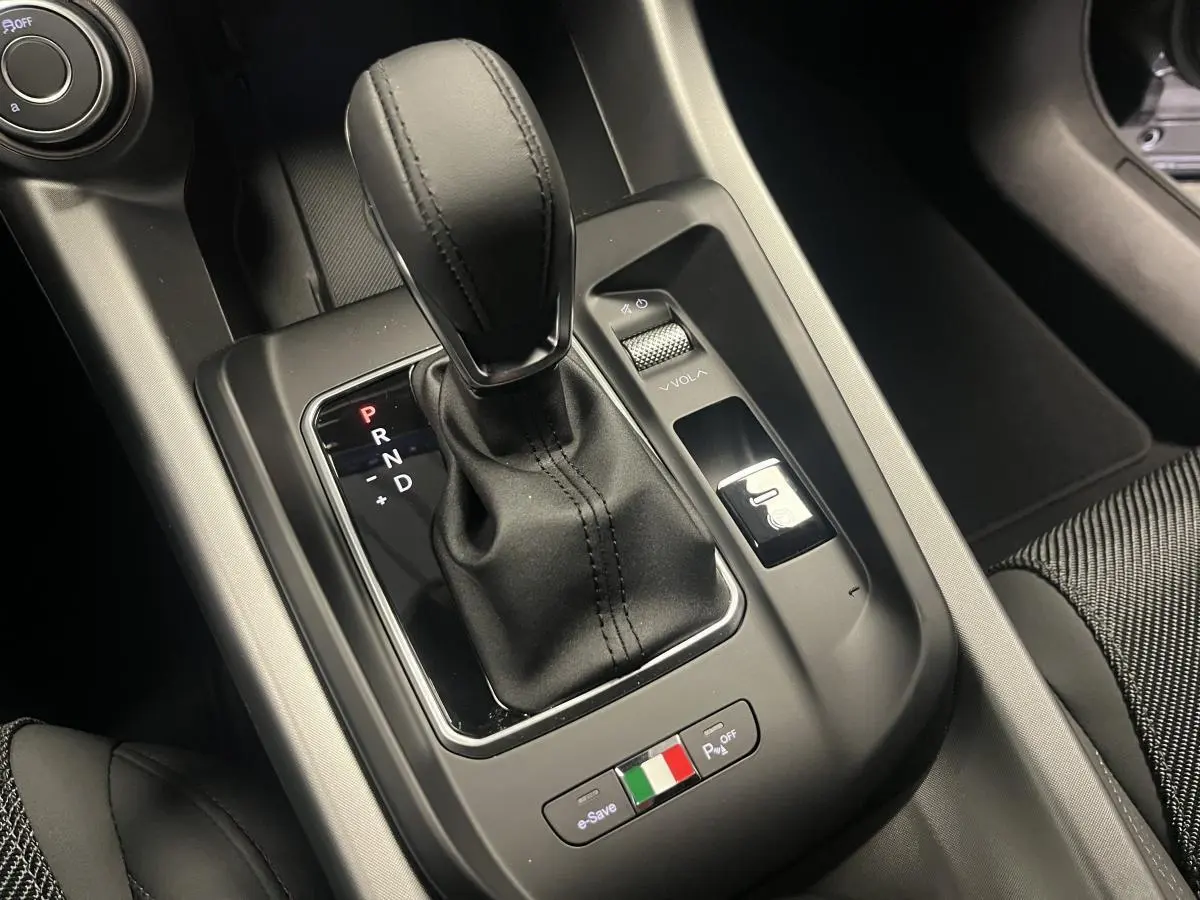 Gros plan sur la console centrale de l'Alfa Romeo Tonale 2023, levier de vitesse cuir et bouton aux couleurs italiennes.