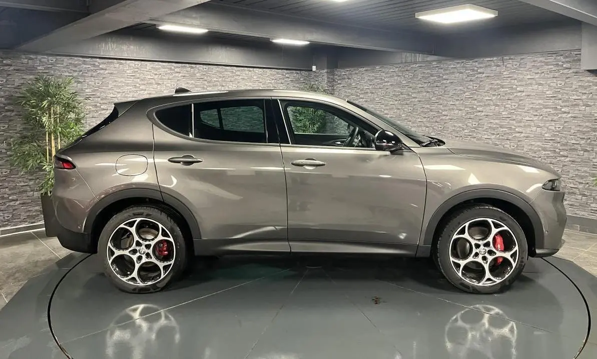 Profil côté gauche de l'Alfa Romeo Tonale gris foncé 2023 avec jantes alliage 19 pouces et étriers rouges visibles.