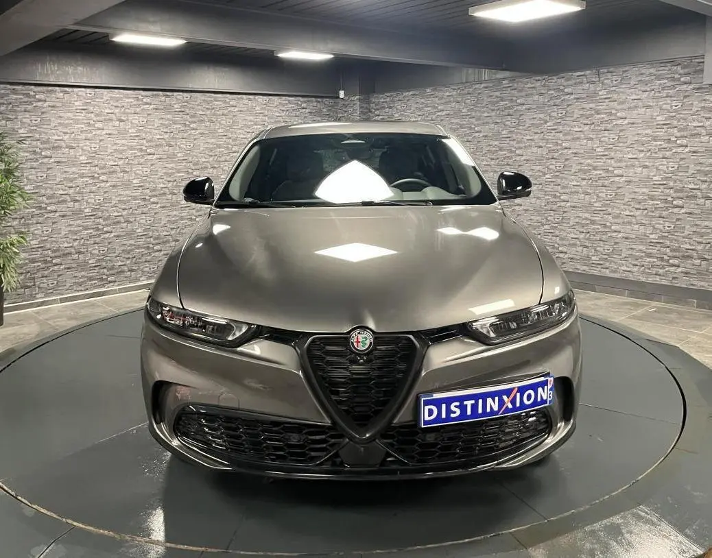 Vue frontale d'une Alfa Romeo Tonale gris foncé avec calandre en V et phares LED dans un showroom.