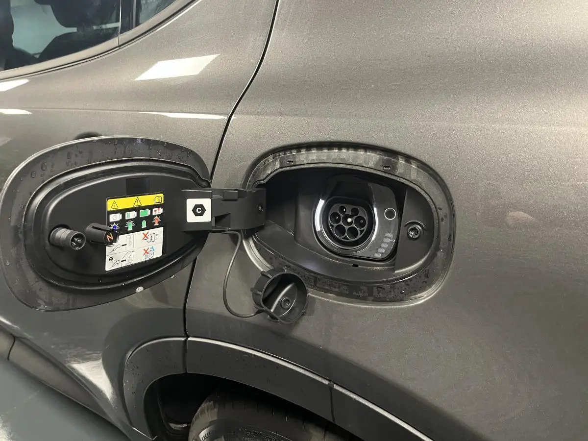 Prise de recharge hybride ouverte côté gauche sur Alfa Romeo Tonale gris foncé, avec port de charge visible.