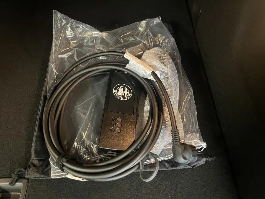 Câble de recharge Alfa Romeo Tonale 1.3 PHEV gris foncé, vu en gros plan sur fond noir intérieur de coffre.