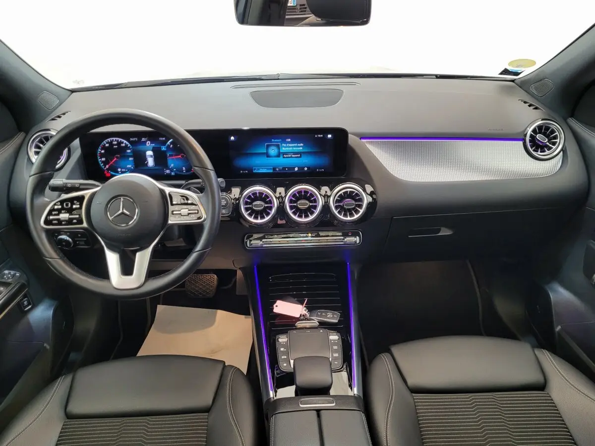 Intérieur avant d'une Mercedes GLA 200 D Business Line 2022, tableau de bord noir avec éclairage d'ambiance violet et écran tactile large.