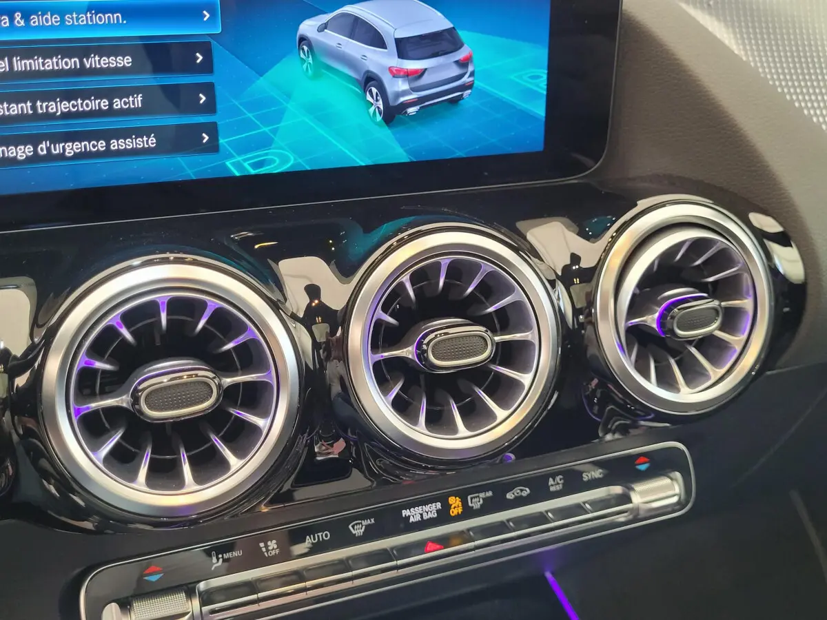 Gros plan sur les aérateurs ronds chromés et l'écran tactile du tableau de bord d'une Mercedes GLA 200 D bleu 2022